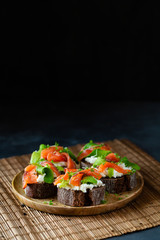 Homemade toast sandwich with rye bread, salmon, avocado, cottage cheese and microgreen sprouts on dark background. Healthy food - breakfast