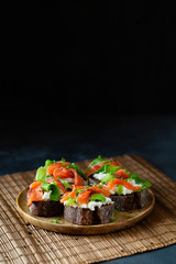 Homemade toast sandwich with rye bread, salmon, avocado, cottage cheese and microgreen sprouts on dark board background. healthy food - breakfast close-up