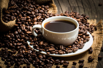 Coffee cup and beans on a rustic background. Coffee Espresso and a piece of cake with a curl. Cup of Coffee and coffee beans on table.