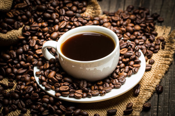 Coffee cup and beans on a rustic background. Coffee Espresso and a piece of cake with a curl. Cup of Coffee and coffee beans on table.