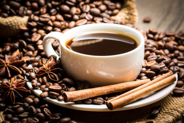 Coffee cup and beans on a rustic background. Coffee Espresso and a piece of cake with a curl. Cup of Coffee and coffee beans on table.