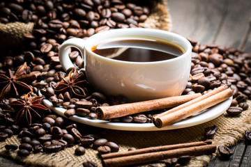 Coffee cup and beans on a rustic background. Coffee Espresso and a piece of cake with a curl. Cup of Coffee and coffee beans on table.