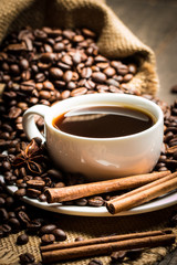 Coffee cup and beans on a rustic background. Coffee Espresso and a piece of cake with a curl. Cup of Coffee and coffee beans on table.