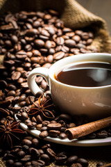 Coffee cup and beans on a rustic background. Coffee Espresso and a piece of cake with a curl. Cup of Coffee and coffee beans on table.