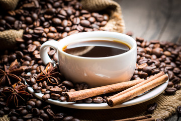 Coffee cup and beans on a rustic background. Coffee Espresso and a piece of cake with a curl. Cup of Coffee and coffee beans on table.