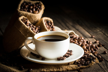 Coffee cup and beans on a rustic background. Coffee Espresso and a piece of cake with a curl. Cup of Coffee and coffee beans on table.