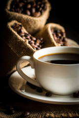 Coffee cup and beans on a rustic background. Coffee Espresso and a piece of cake with a curl. Cup of Coffee and coffee beans on table.