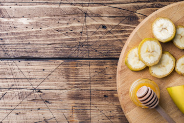 Banana and sliced banana into pieces with honey on wooden background, copy space.