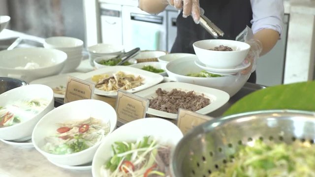 Cook putting food in bowl in buffet while lunch in all inclusive resort hotel restaurant. Restaurant food for traditional brunch, lunch and dinner in luxury hotel.