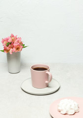 Obraz na płótnie Canvas Cup of coffee, white marshmallow, flowers on grey stone table