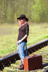 beautiful young girl with a suitcase on the railroad tracks	