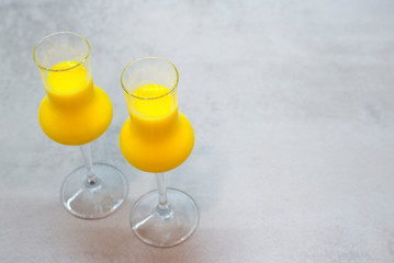 Two glasses of egg liqueur on light grey texture background