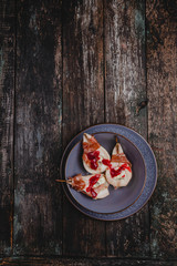 Fototapeta na wymiar baked pears with blue cheese and prosciutto ham in bowl with lemons. grape and textile on wooden background