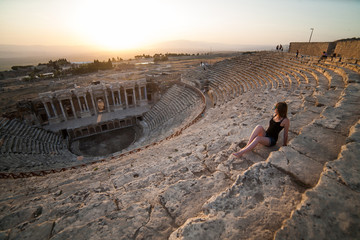 Girl sits on the steps of the amphitheater Travel to Turkey, the monuments of ancient architecture