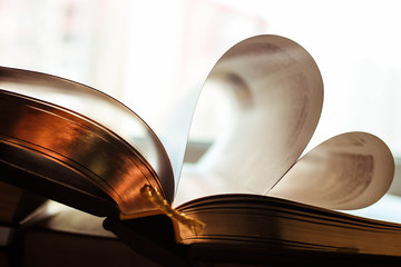 Large book with golden pages in the image of the heart. Shiny wite background.