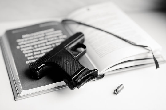 Detective novel concept with gun, book and bullet. Black and white photo.