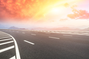Empty asphalt road and mountains with beautiful clouds at sunset