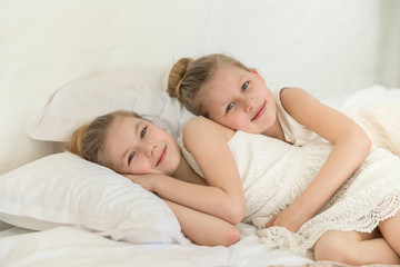 Two little six years old sisters in the bed lay on the pillows