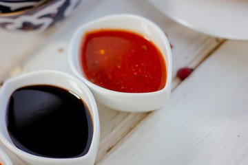 Different dips and sauces - red, white and black over white table.