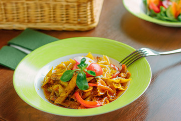 Farfalle pasta with the chicken and tomatoes on a green plate.