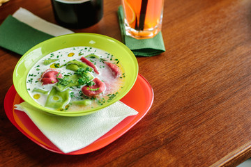 Green and red ravioli in soup for kids.