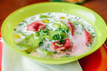 Green and red ravioli in soup for kids.