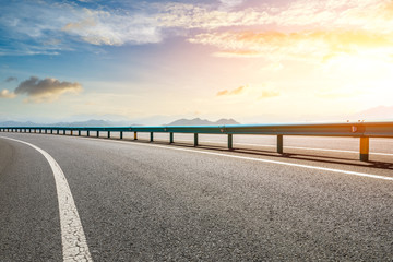 Empty asphalt road and mountains with beautiful clouds at sunset © ABCDstock