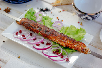 Meat kebab on sckewer, chiken kebab on white plate.