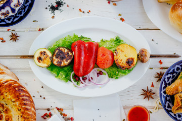 Top view of grilled vegetables on sckewer over the white plate.