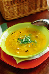 Vegetable soup in a green plate over a wooden table.