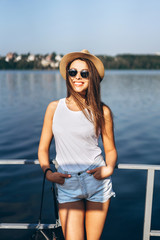 Cute young brunette girl relaxing on the pier near lake.