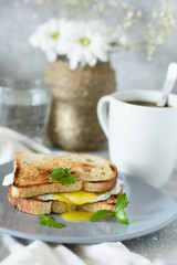 Toast with egg and coffee for breakfast on a gray concrete background and a vase of flowers