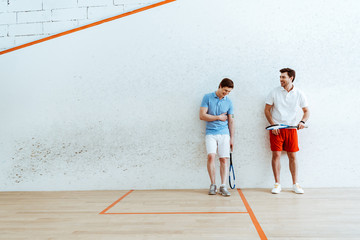 Full length view of smiling squash players in polo shirts