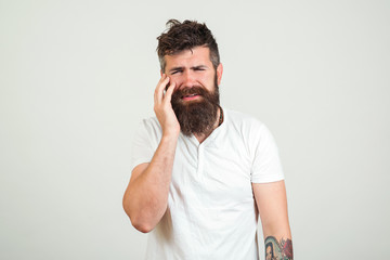 Sad bearded man having toothache, on white background. Toothache concept. Frustrated young guy touching his cheek and keeping eyes. Man feeling pain, suffering from bad tooth ache.