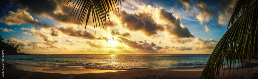 Wall mural sunset through a palm leaf on paradise beach 1