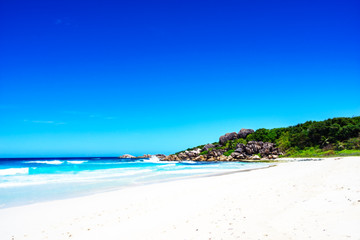 White sand, palm trees, granite rocks and turquoise water at the paradise beach at grand anse, la digue, seychelles 3