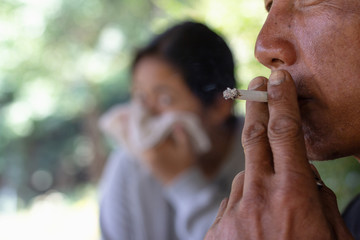 Passive smoking concept. Man is smoking cigarette and woman is covering her face. Concepts stop smoking in public places.