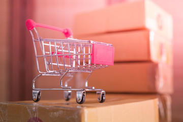 mini red shopping cart with cardboard boxes in background