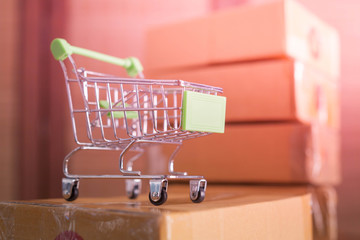 mini green shopping cart with cardboard boxes in background