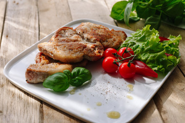 Fried pork. Cherry. Basil. Homemade dish. Wooden table.