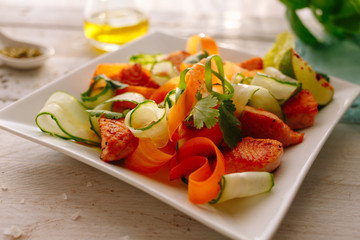 Salad with grilled chicken and vegetables. Cucumber, carrot, lime. Wooden white table. Ingridients.