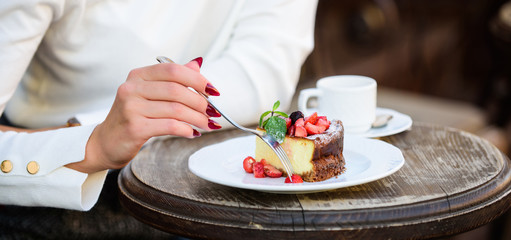 Obraz na płótnie Canvas Dessert cake cup of coffee and female hand with fork close up. Piece of cake with red berry. Gourmet recipe food. Cake slice on white plate. Cake with cream delicious dessert. Appetite concept
