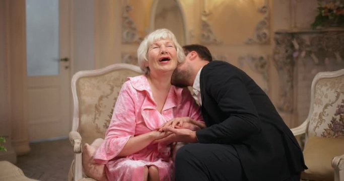 Unequal marriage. Young man whispering compliments