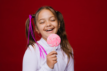 Funny child with candy lollipop, happy little girl eating big sugar lollipop, kid eat sweets. surprised child with candy. isolated on bright background, studio. Beautiful little girl with lollipop 