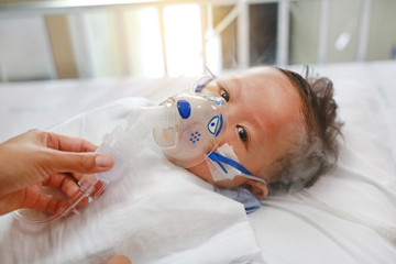 Sick baby boy applying inhale medication by inhalation mask to cure Respiratory Syncytial Virus...