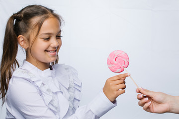 Funny child with candy lollipop, happy little girl eating big sugar lollipop, kid eat sweets. surprised child with candy. isolated on bright background, studio. Beautiful little girl with lollipop 