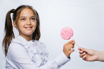 Funny child with candy lollipop, happy little girl eating big sugar lollipop, kid eat sweets. surprised child with candy. isolated on bright background, studio. Beautiful little girl with lollipop 