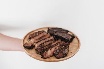 A man holding a wooden plate that has rib eye steak on it - Carnivore Diet