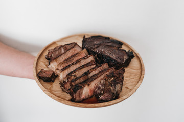 A man holding a wooden plate that has rib eye steak on it - Carnivore Diet