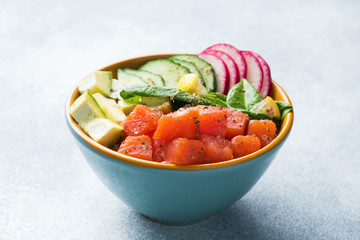 Traditional Hawaiian Poke salad with salmon, avocado rice and vegetables in a bowl.